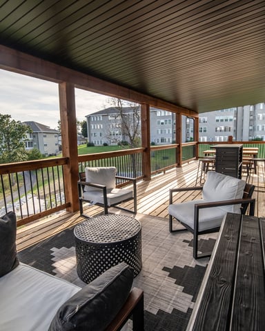 Covered deck with lounge seating, dining area, and view of residential neighborhood and distant hills