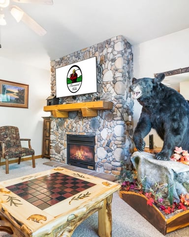Living room with stone fireplace, taxidermied bear display, decorative chess table, and rustic lodge decor