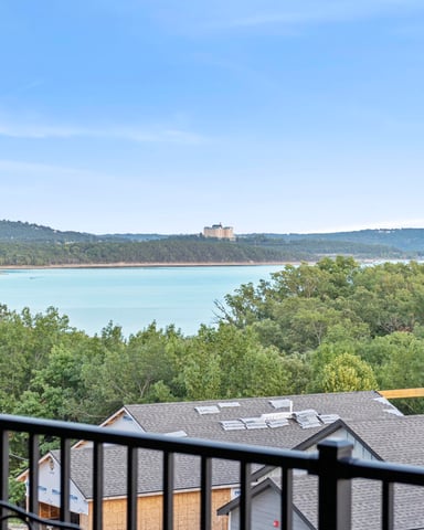 Deck railing with view of turquoise lake, forested shoreline, and resort building on distant hillside